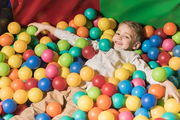 Cute happy little boy playing in pool with colorful balls — Stock Photo