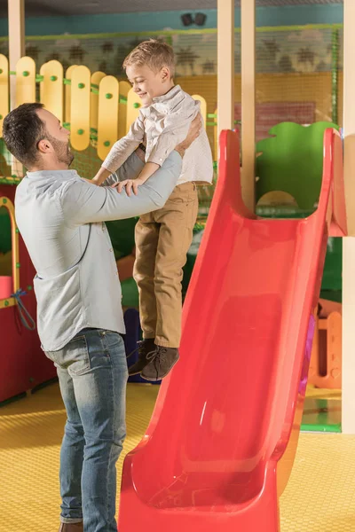 Heureux père portant petit fils dans le centre de divertissement — Photo de stock