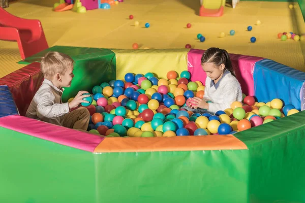 Mignons petits enfants jouant dans la piscine avec des boules colorées — Photo de stock