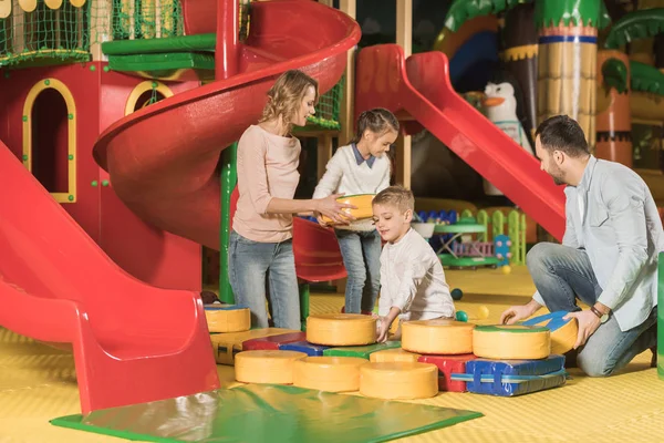 Famille heureuse avec deux petits enfants jouant ensemble dans le centre de jeu — Photo de stock