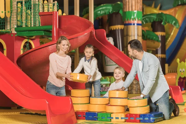 Happy parents with adorable little kids playing together in game center — Stock Photo