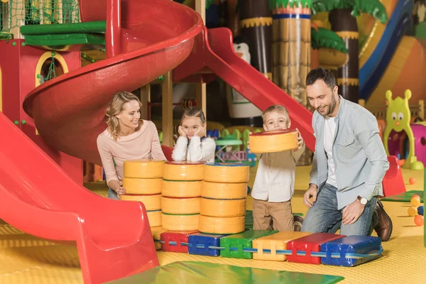 Família feliz com duas crianças brincando juntas no centro de entretenimento — Fotografia de Stock