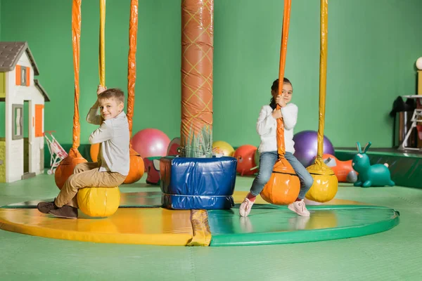 Adorable smiling siblings swinging and playing in entertainment center — Stock Photo