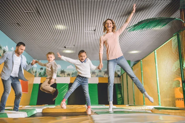 Famille heureuse tenant la main et sautant ensemble dans le centre de divertissement — Photo de stock