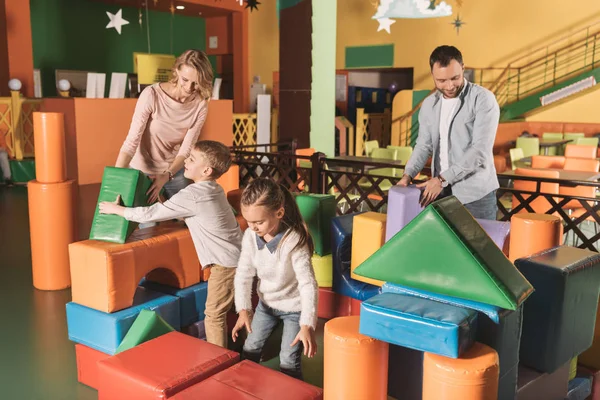 Família feliz com duas crianças brincando com blocos coloridos no centro de jogos — Fotografia de Stock