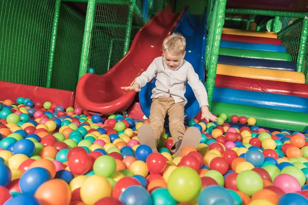 Cute happy little boy playing in pool with colorful balls — Stock Photo