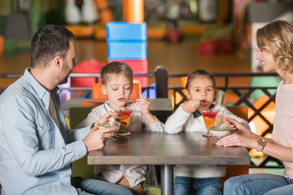 Famiglia felice con due bambini che mangiano dolci nel caffè — Foto stock