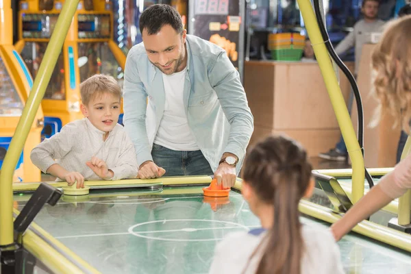 Schnappschuss einer Familie mit zwei Kindern beim gemeinsamen Airhockey im Spielcenter — Stockfoto
