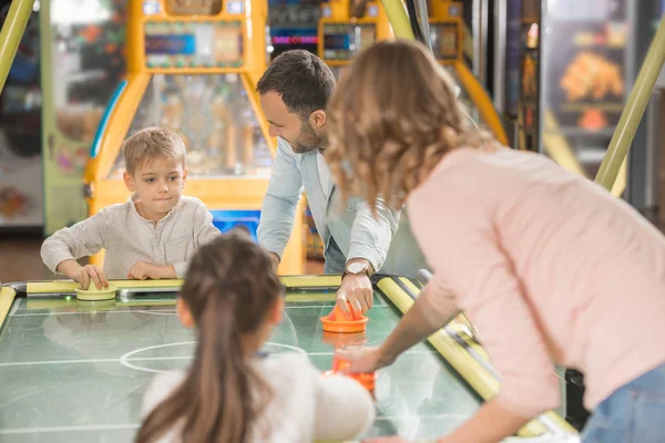 Glückliche Familie mit zwei Kindern beim gemeinsamen Airhockey im Spielcenter — Stockfoto