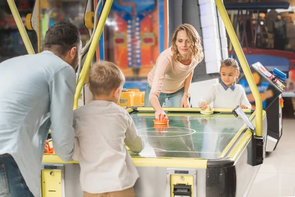 Happy family playing air hockey together in entertainment center — Stock Photo