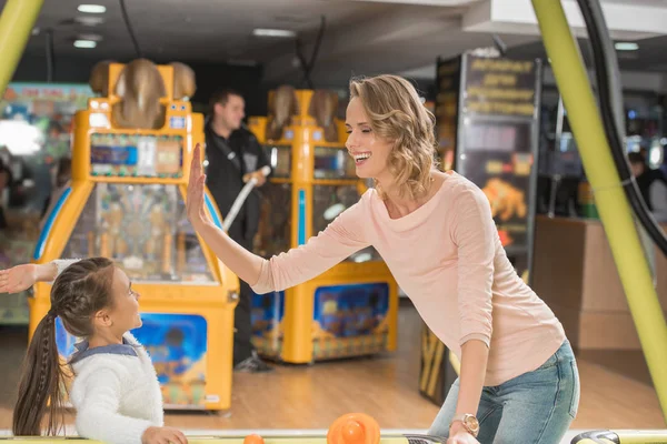 Happy mother and daughter giving high five while playing air hockey together — Stock Photo