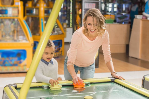 Glückliche Mutter und Tochter spielen gemeinsam Airhockey im Unterhaltungszentrum — Stockfoto