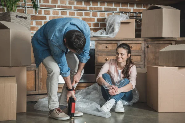 Young couple with bottle of wine celebrating relocation in new house — Stock Photo