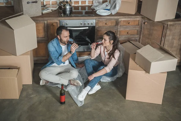 Vista de ángulo alto de la joven pareja bebiendo vino y celebrando la reubicación en un apartamento nuevo — Stock Photo
