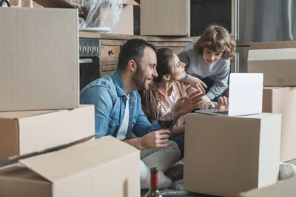 Famille heureuse avec un enfant utilisant un ordinateur portable ensemble dans une nouvelle maison — Photo de stock