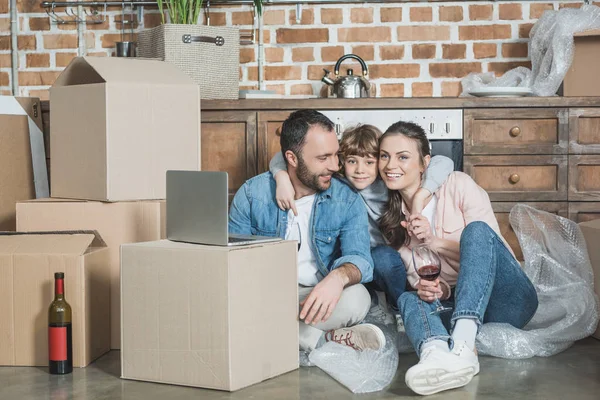 Glückliche Familie lächelt in Kamera und benutzt gemeinsam Laptop in neuer Wohnung — Stockfoto