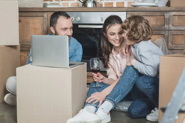 Familia feliz usando el ordenador portátil juntos en la nueva casa - foto de stock