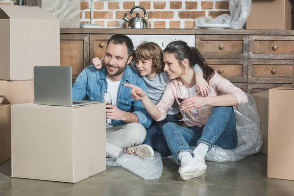 Happy family using laptop while sitting in new house — Stock Photo