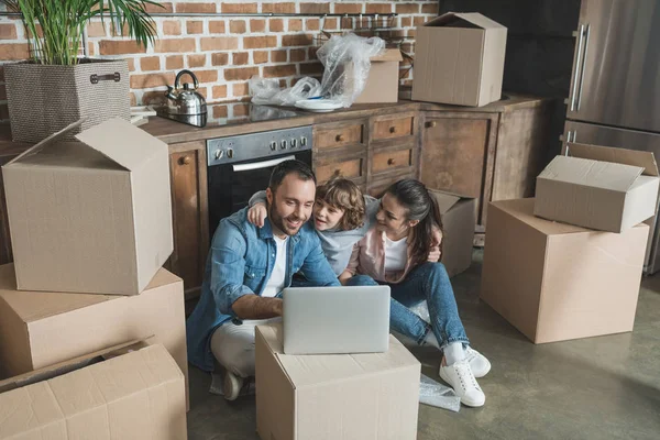 Vista de ángulo alto de la familia feliz usando el ordenador portátil en el nuevo apartamento - foto de stock