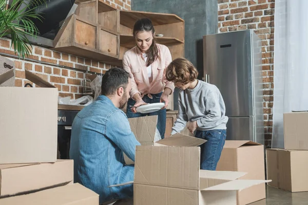 Happy family unpacking cardboard boxes in new house — Stock Photo