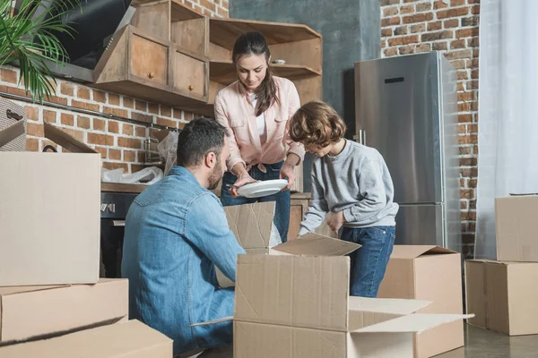 Família feliz desempacotando caixas de papelão em nova casa — Fotografia de Stock