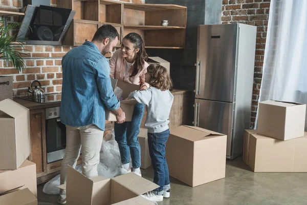 Cajas de cartón de embalaje feliz familia mientras se muda a casa - foto de stock