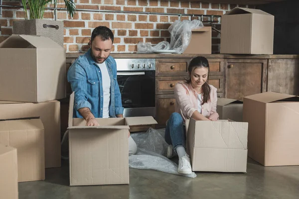 Happy young couple packing cardboard boxes during relocation — Stock Photo