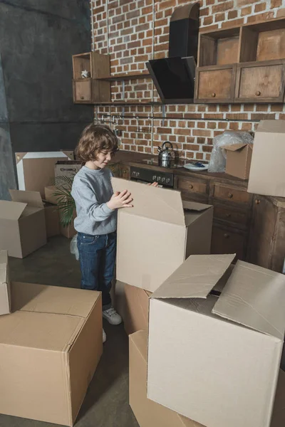 Adorable little boy unpacking cardboard boxes in new apartment — Stock Photo