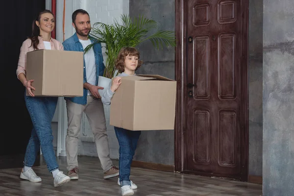 Счастливая семья с картонными коробками и горшок завод переезда домой — стоковое фото