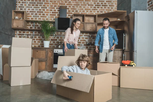 Happy parents packing boxes and son playing with toy car while relocating — Stock Photo