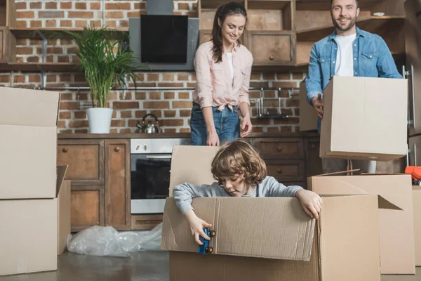 Glückliche Familie mit einem Kind beim Kistenpacken während des Umzugs — Stockfoto