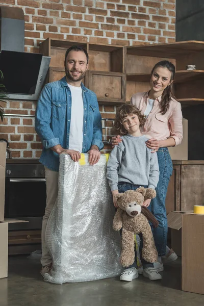 Happy family with one child smiling at camera while moving home — Stock Photo