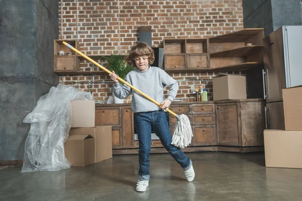 Cute happy little boy playing with mop in new apartment — Stock Photo