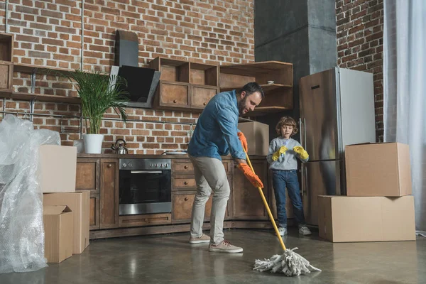 Père et fils dans des gants en caoutchouc nettoyage nouvelle maison après la relocalisation — Photo de stock