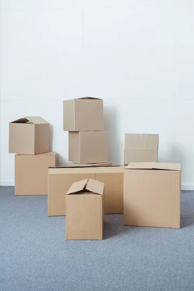 Cajas de cartón apiladas en la habitación vacía durante la reubicación - foto de stock