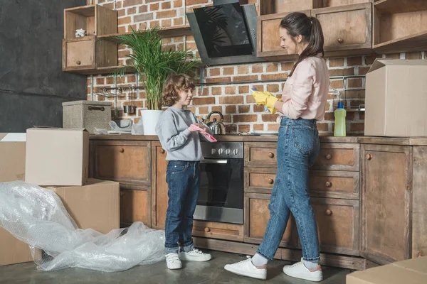 Heureux mère et fils laver les assiettes après la réinstallation dans le nouvel appartement — Photo de stock