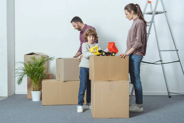 Happy family with one child packing cardboard boxes during relocation — Stock Photo