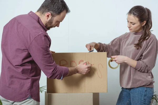 Giovani scatole di imballaggio coppia mentre si trasferisce in una nuova casa — Foto stock