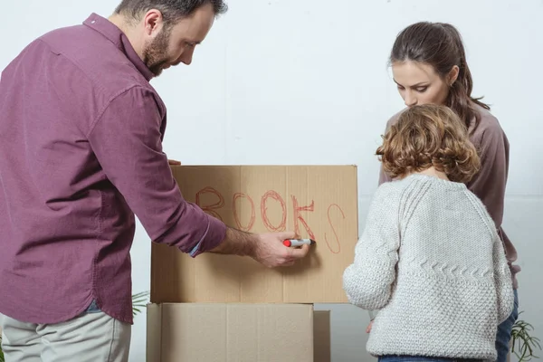 Family with one kid singing cardboard box while moving in new home — Stock Photo