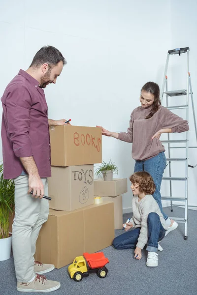 Happy family packing boxes while moving in new home — Stock Photo