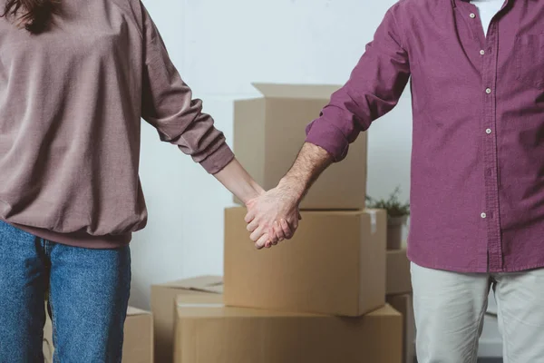 Cropped shot of couple holding hands while moving home — Stock Photo