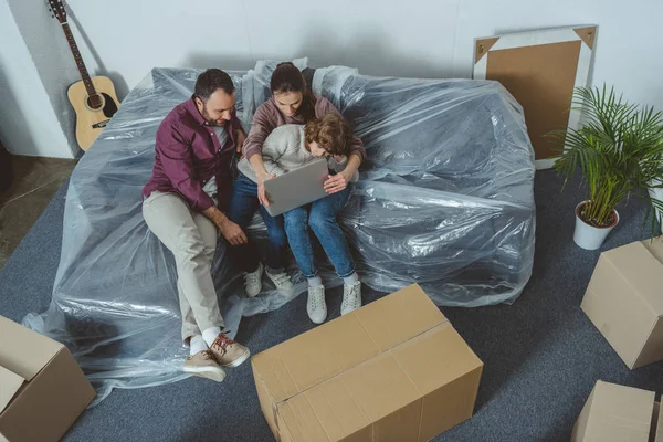 High angle view of family with one child using laptop while moving in new home — Stock Photo