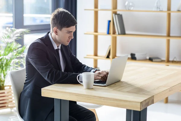 Jeune homme d'affaires travaillant sur ordinateur portable dans un bureau moderne — Photo de stock