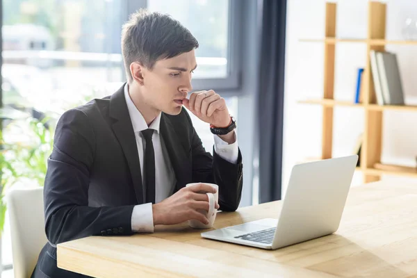 Jungunternehmer schaut auf Laptop-Bildschirm im modernen Büro — Stockfoto