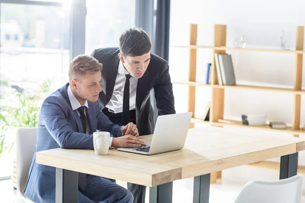 Young businessmen working on laptop in modern office — Stock Photo