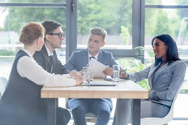 Behind the glass view of concentrated business people discussing project in modern office — Stock Photo