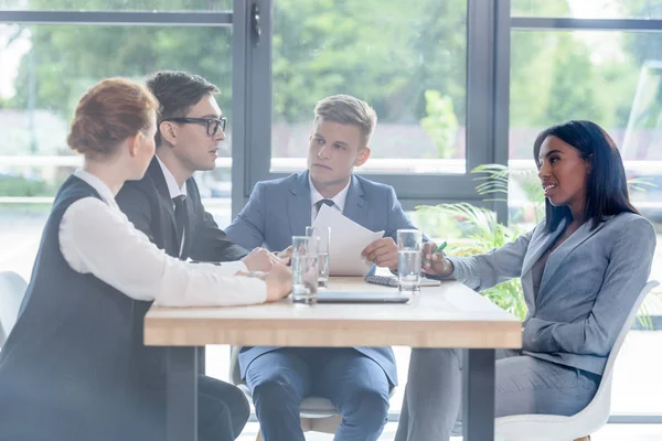 Derrière la vue en verre des gens d'affaires concentrés discutant du projet dans le bureau moderne — Photo de stock