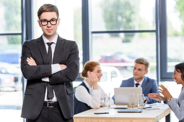 Uomo d'affari fiducioso di fronte ai suoi colleghi in ufficio moderno — Foto stock