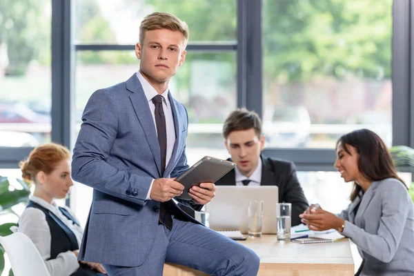 Un hombre de negocios confiado frente a sus colegas en la oficina moderna - foto de stock