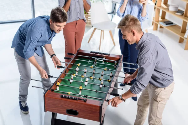 Gente de negocios jugando futbolín en oficina moderna - foto de stock